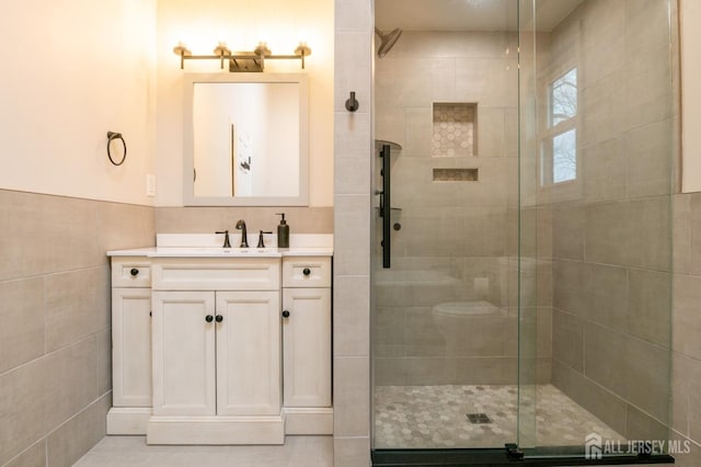 full bathroom with vanity, a shower stall, and tile walls