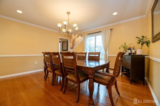 dining room featuring a notable chandelier, crown molding, baseboards, and wood finished floors