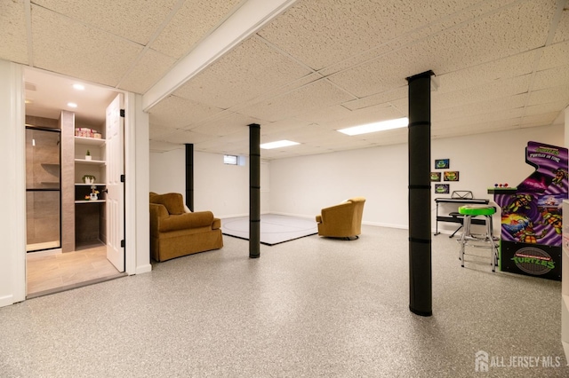 finished below grade area featuring a drop ceiling and baseboards