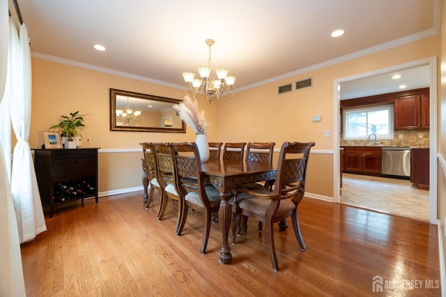 dining area with light wood-style flooring, crown molding, baseboards, and a notable chandelier