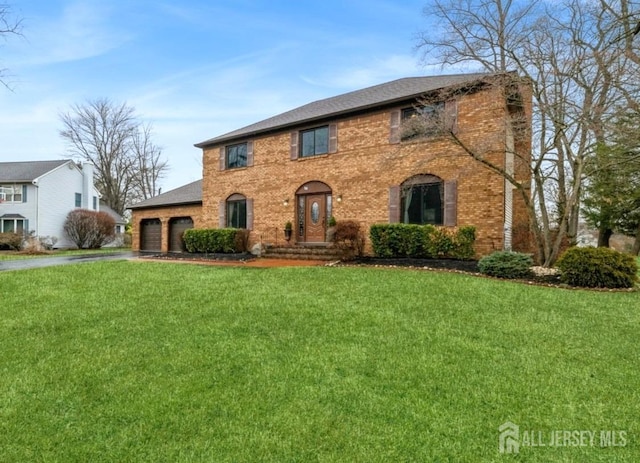 view of front of home with driveway, a garage, a front lawn, and brick siding