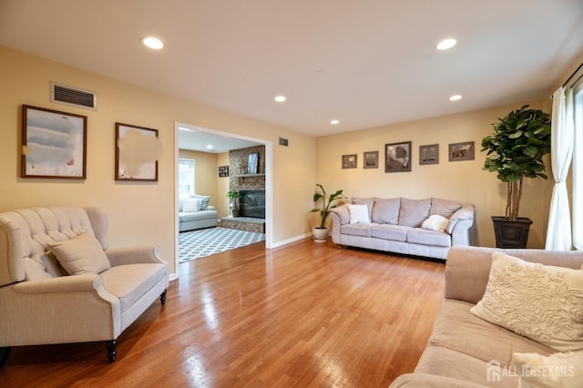 living area with a large fireplace, visible vents, wood finished floors, and recessed lighting