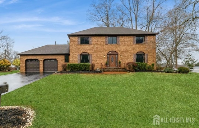 view of front of property with an attached garage, brick siding, aphalt driveway, and a front yard