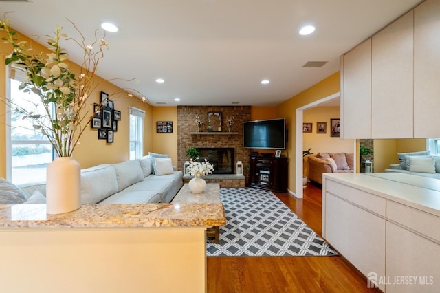 living area with recessed lighting, visible vents, a fireplace, and wood finished floors