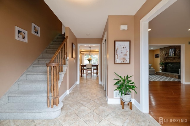 entrance foyer with stairs, a fireplace, light wood-style flooring, and baseboards