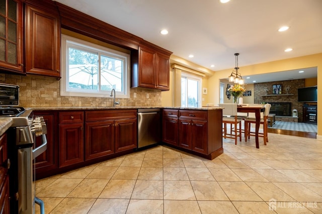 kitchen featuring tasteful backsplash, appliances with stainless steel finishes, light stone countertops, a sink, and light tile patterned flooring