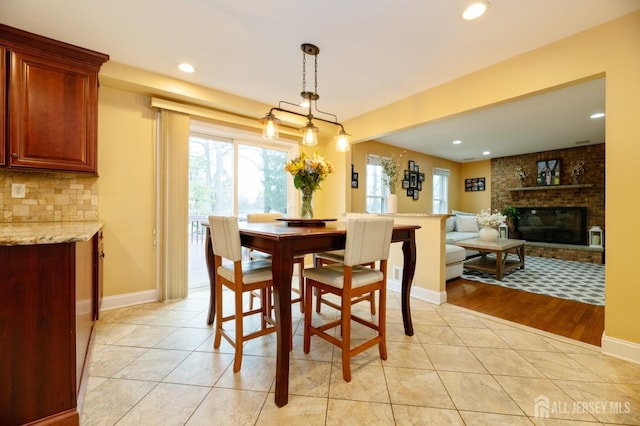 dining area with recessed lighting, a brick fireplace, baseboards, and light tile patterned floors