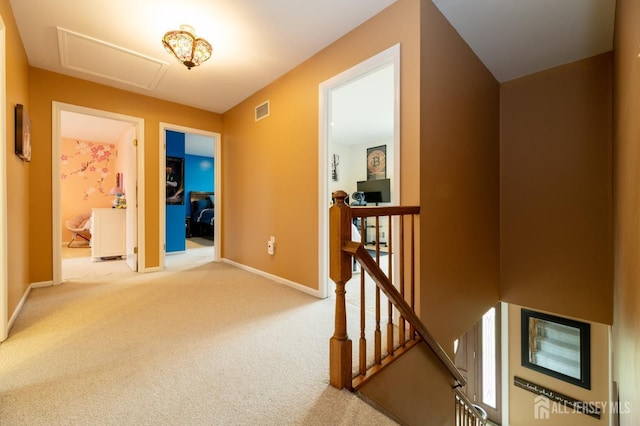 corridor with carpet, visible vents, attic access, an upstairs landing, and baseboards