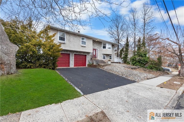 raised ranch featuring a front yard, an attached garage, stone siding, and driveway