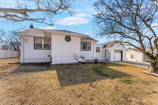 view of front of property with driveway, fence, roof with shingles, a front yard, and a chimney