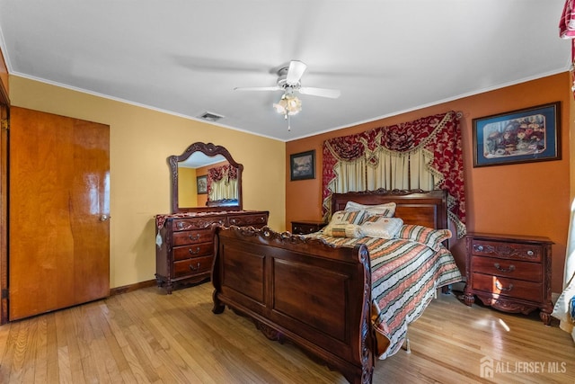 bedroom featuring visible vents, baseboards, wood finished floors, and ornamental molding