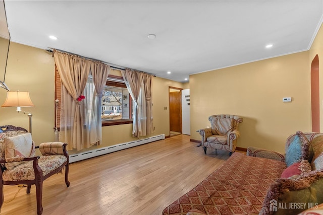 living area with wood finished floors, recessed lighting, arched walkways, crown molding, and a baseboard radiator