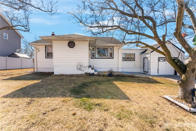 view of front of house with roof with shingles, a front yard, and fence