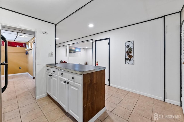 kitchen with dark countertops, white cabinets, light tile patterned flooring, and baseboards