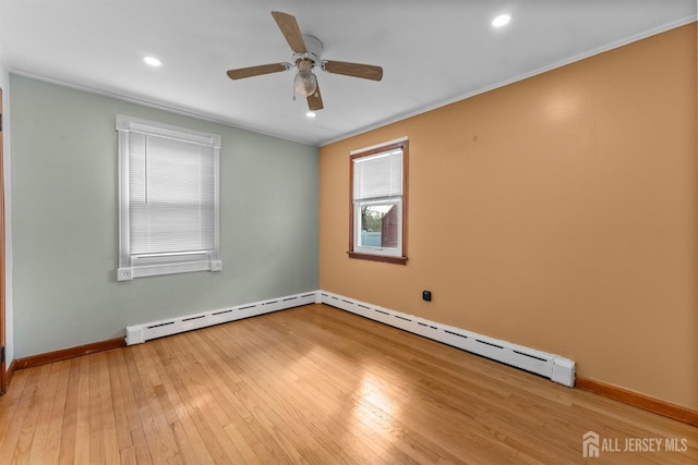 empty room featuring baseboard heating, baseboards, a ceiling fan, and hardwood / wood-style floors