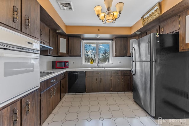 kitchen featuring dark brown cabinets, visible vents, black appliances, and a sink