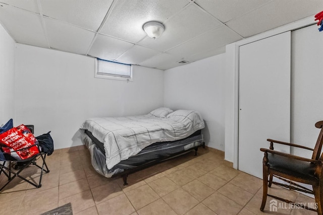 bedroom with light tile patterned flooring, visible vents, and a paneled ceiling