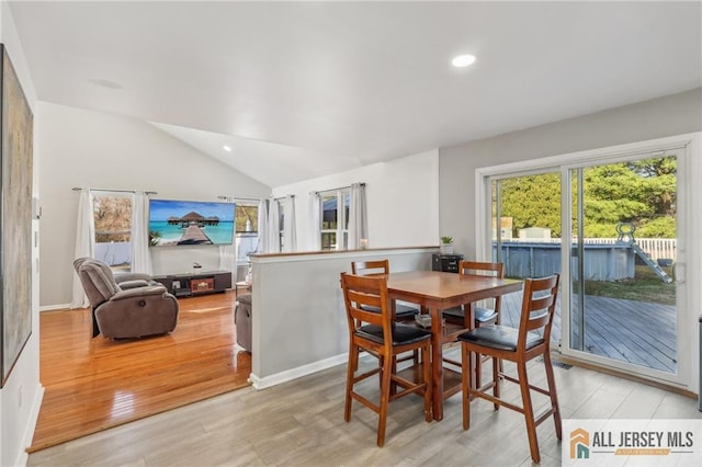 dining area with light wood-type flooring and vaulted ceiling