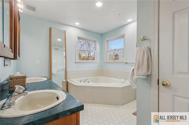 bathroom featuring tile patterned floors, vanity, and a relaxing tiled tub