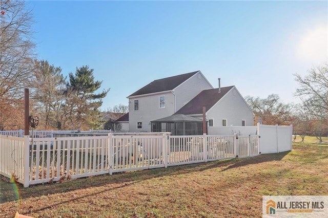 back of property with a sunroom and a lawn