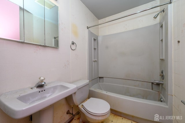 bathroom with a sink, bathing tub / shower combination, tile walls, and toilet