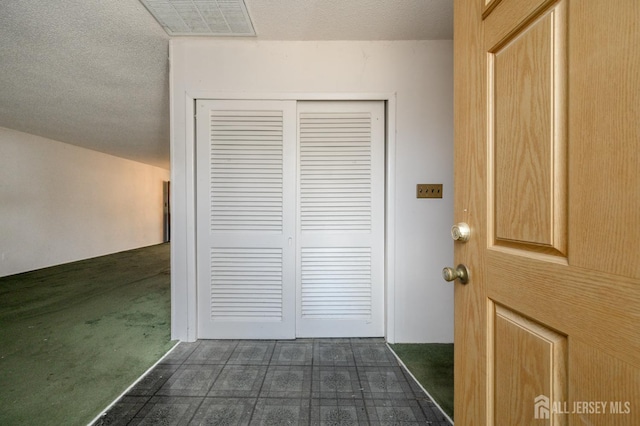 interior space with dark colored carpet, visible vents, and a textured ceiling