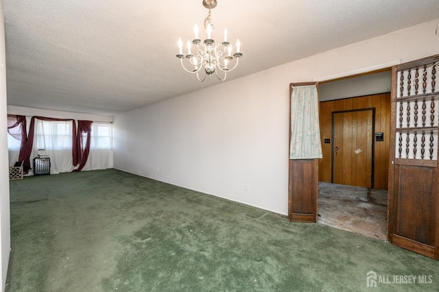 spare room featuring a textured ceiling, a chandelier, and carpet flooring