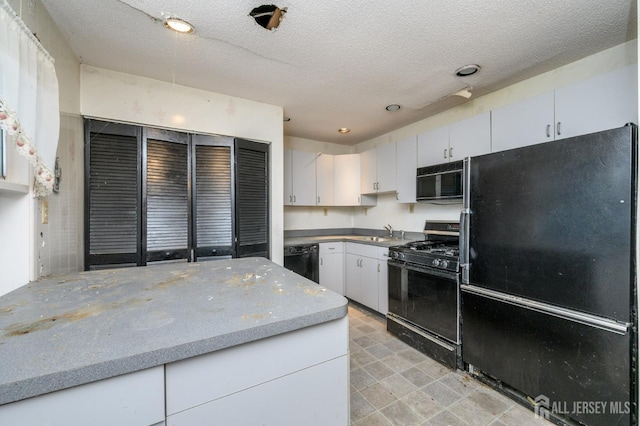 kitchen with light stone counters, a sink, black appliances, white cabinets, and a textured ceiling