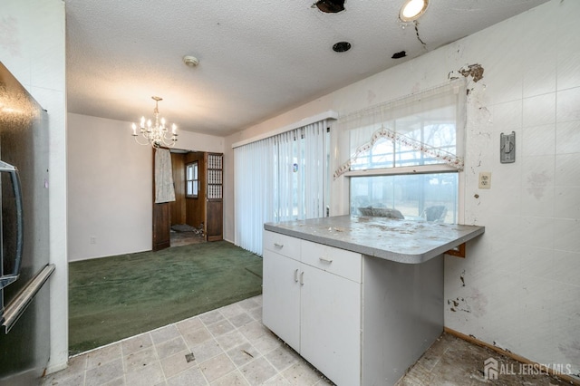 kitchen with a wealth of natural light, light colored carpet, a textured ceiling, and white cabinetry