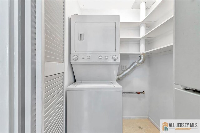 clothes washing area with stacked washing maching and dryer, baseboards, and laundry area