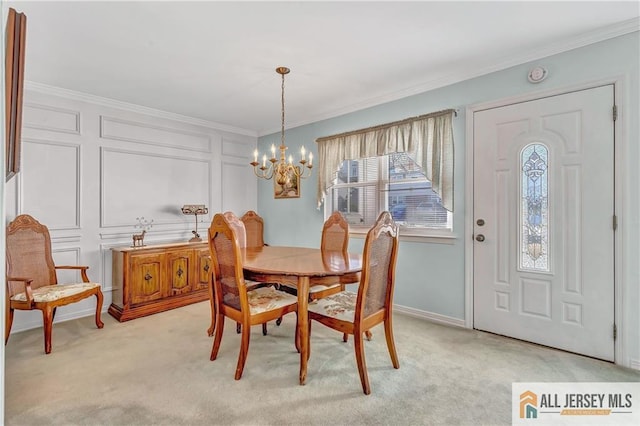 dining room featuring a chandelier, ornamental molding, light colored carpet, and a decorative wall