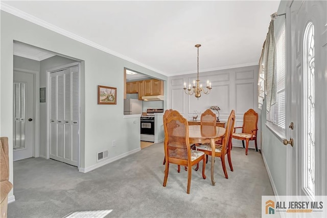 dining space with light carpet, an inviting chandelier, baseboards, and crown molding