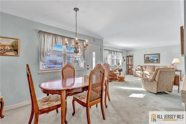 dining space with an inviting chandelier, ornamental molding, a wealth of natural light, and light colored carpet