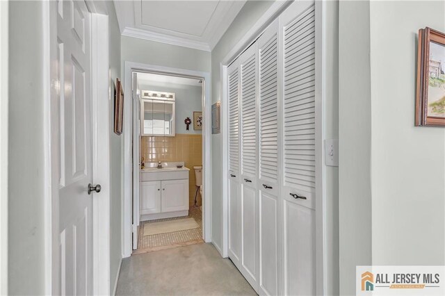 hallway with tile walls, a sink, light colored carpet, and crown molding