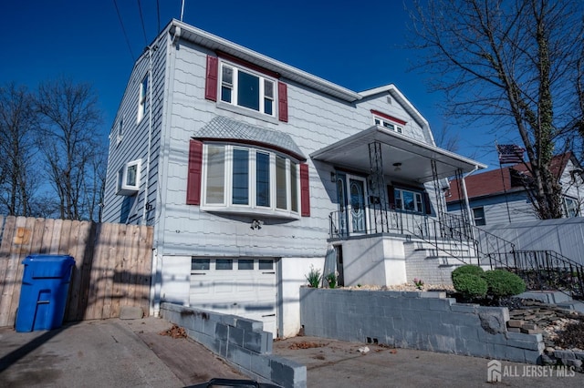view of front of home featuring stairway, covered porch, an attached garage, fence, and a wall mounted AC