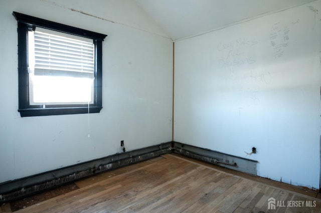 spare room with vaulted ceiling and wood finished floors