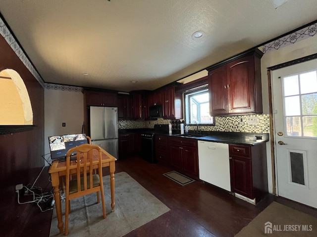 kitchen with dark countertops, freestanding refrigerator, gas range, black microwave, and dishwasher