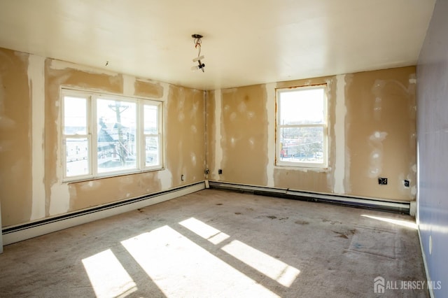 carpeted spare room featuring a baseboard heating unit and a healthy amount of sunlight