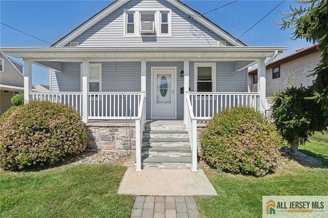 bungalow with a porch, cooling unit, and a front lawn