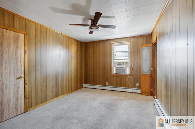 carpeted empty room with cooling unit, baseboard heating, ceiling fan, and wooden walls