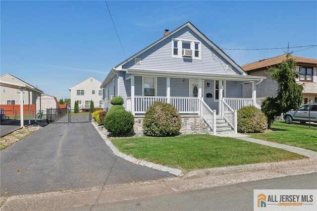 bungalow featuring covered porch, cooling unit, and a front yard