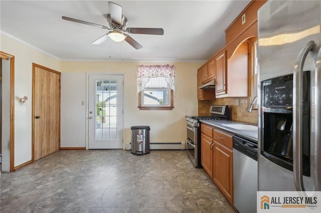 kitchen featuring a sink, stainless steel appliances, baseboard heating, under cabinet range hood, and backsplash