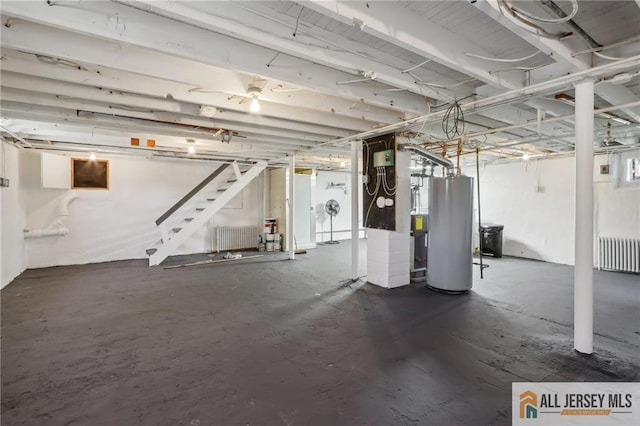 unfinished basement featuring stairs, radiator, and water heater