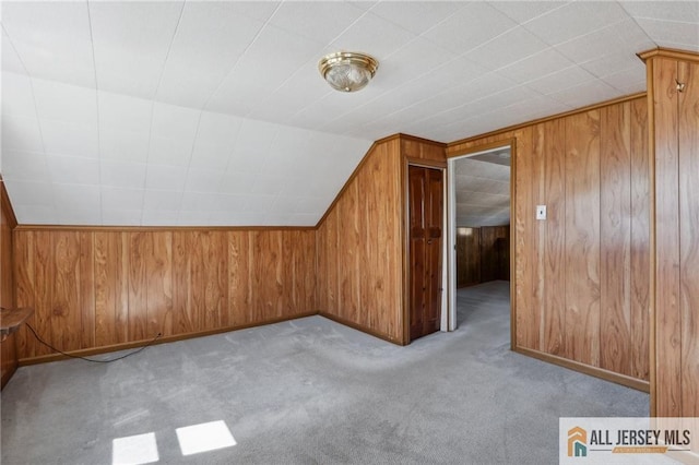 bonus room featuring lofted ceiling, carpet floors, and wood walls