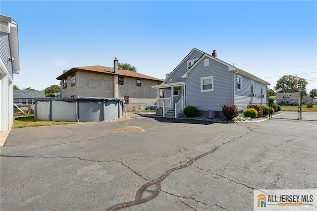 back of property with a covered pool, a chimney, and fence