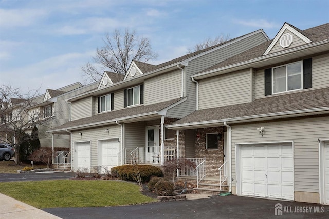 townhome / multi-family property with a garage, driveway, and a shingled roof