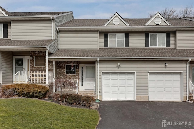 multi unit property featuring a front lawn, driveway, a shingled roof, and a garage