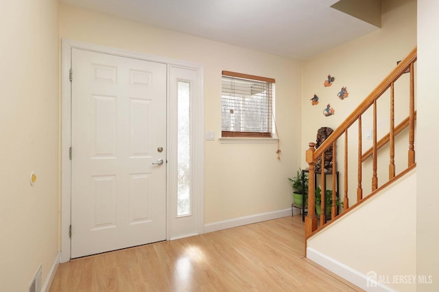 entrance foyer with visible vents, baseboards, wood finished floors, and stairs