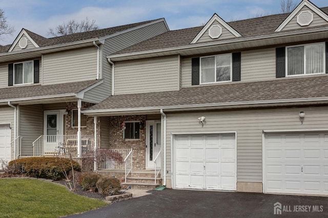 view of front of house with an attached garage, brick siding, driveway, and a shingled roof