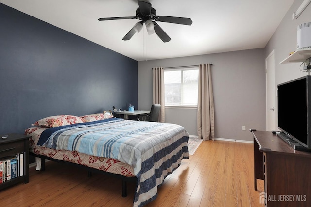 bedroom with ceiling fan, baseboards, and light wood-style floors